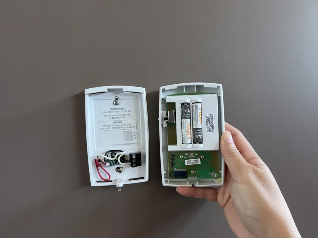 homeowner changing thermostat batteries