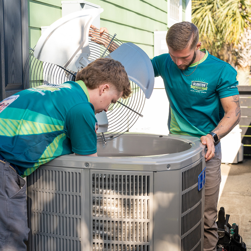 Two of Blanton's technicians fixing HVAC condensor