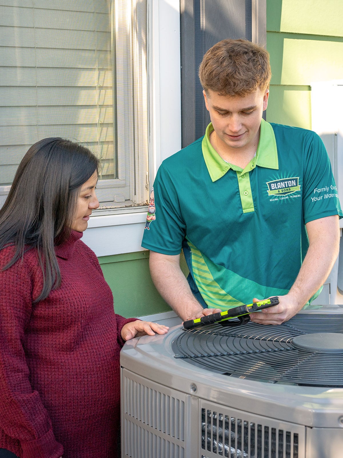 Blanton's technician showing HVAC test results in a tablet to customer
