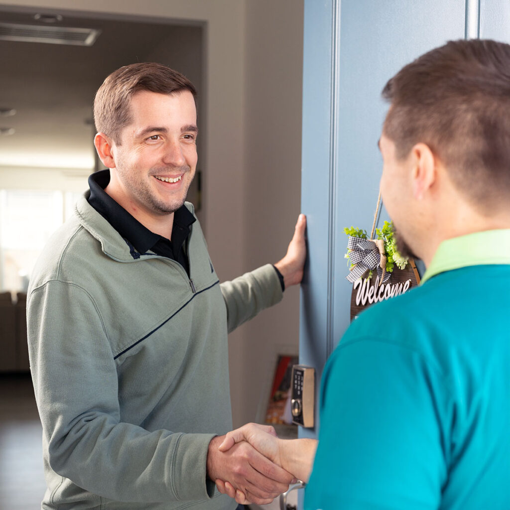 Blanton's HVAC technician greeting customer at the door with a handshake.