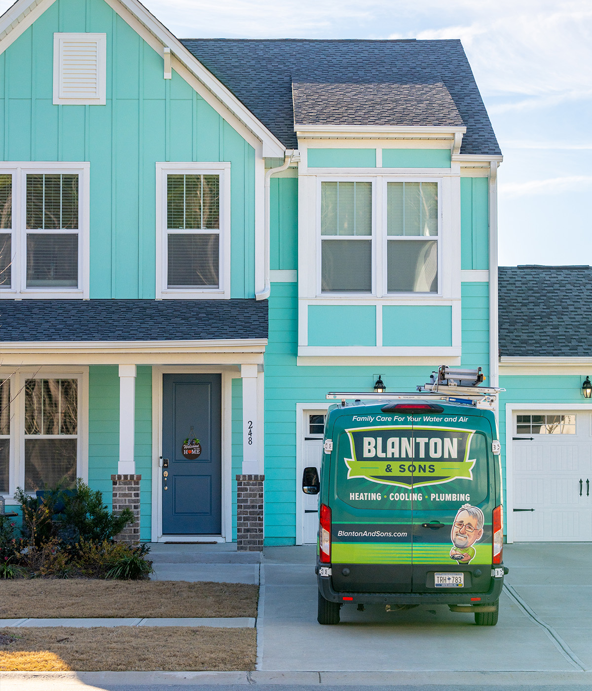 A Blanton & Sons branded service van for heating, cooling, and plumbing parked in the driveway of a teal two-story home