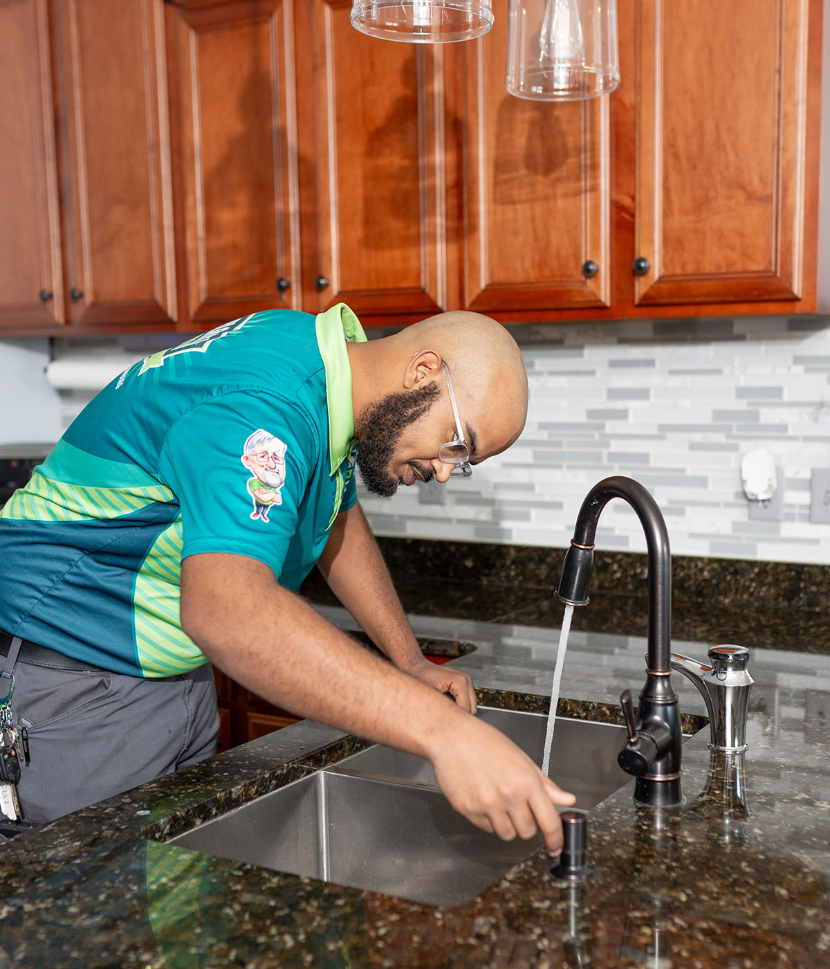 Blanton & Sons plumber inspecting water flow from an oil-rubbed bronze kitchen faucet over a stainless steel sink