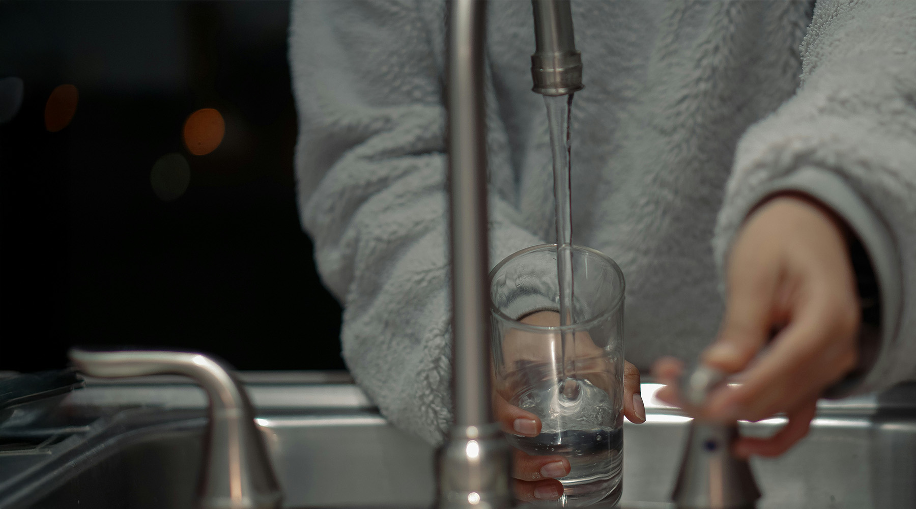 home owner getting a water from the faucet after Blanton and Sons installed a HALO water system