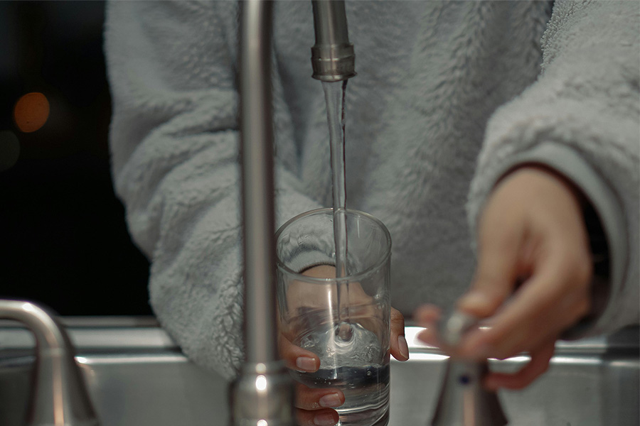 home owner getting a water from the faucet after Blanton and Sons installed a HALO water system